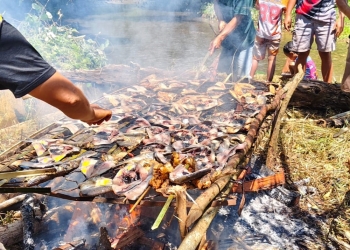 Warga Desa Walandawe, Kecamatan Routa, bekerja sama membakar ikan segar di atas bara api tradisional dalam perayaan pesta panen padi tahunan. Foto: Dok Istimewa/kendarinesia